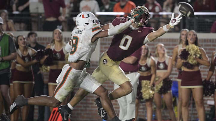 Oct 4, 2025; Tallahassee, Florida, USA; Florida State Seminoles wide receiver Duce Robinson reaches for a pass against Miami Hurricanes defensive back Jakobe Thomas (8) during the second half at Doak S. Campbell Stadium. Mandatory Credit: Melina Myers-Imagn Images