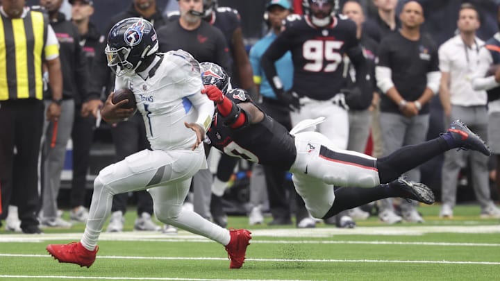 Sep 28, 2025; Houston, Texas, USA; Tennessee Titans quarterback Cam Ward (1) runs with the ball as at Houston Texans linebacker Azeez Al-Shaair (0) attempts to make a tackle during the fourth quarter NRG Stadium. Mandatory Credit: Troy Taormina-Imagn Images