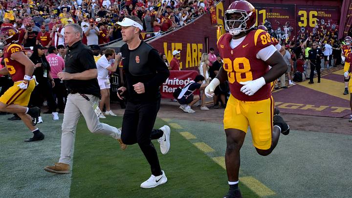 Oct 11, 2025; Los Angeles, California, USA; USC Trojans head coach Lincoln Riley, center, runs on to the field for the game against the Michigan Wolverines at United Airlines Field at the Los Angeles Memorial Coliseum. Mandatory Credit: Jayne Kamin-Oncea-Imagn Images