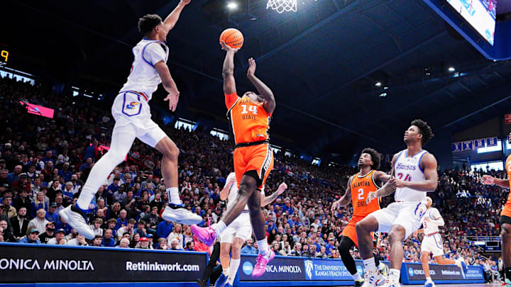 Feb 22, 2025; Lawrence, Kansas, USA; Oklahoma State Cowboys guard Jamyron Keller (14) shoots a layup as Kansas Jayhawks guard Rylan Griffen (6) defends during the first half at Allen Fieldhouse. Mandatory Credit: Denny Medley-Imagn Images