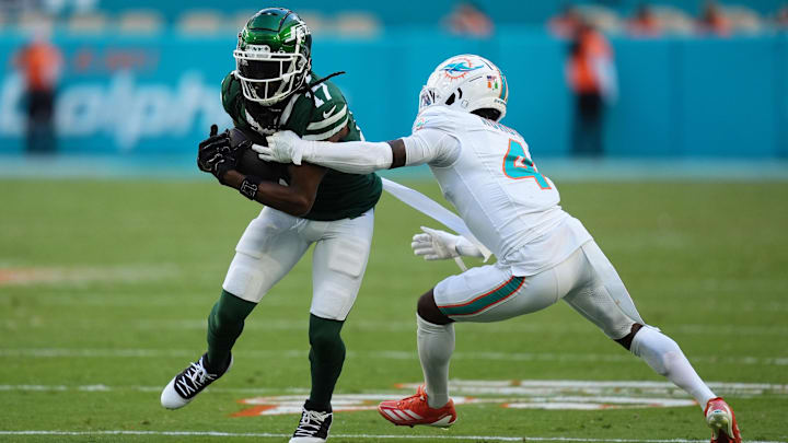 Dec 8, 2024; Miami Gardens, Florida, USA; Miami Dolphins cornerback Kader Kohou (4) attempts to tackle New York Jets wide receiver Davante Adams (17) during the second half at Hard Rock Stadium. Mandatory Credit: Jasen Vinlove-Imagn Images