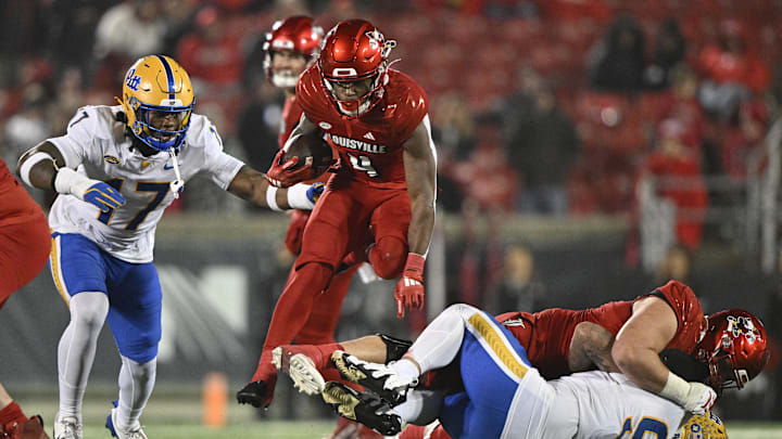 Nov 23, 2024; Louisville, Kentucky, USA; Louisville Cardinals running back Maurice Turner (4) leaps over Pittsburgh Panthers defensive lineman Isaiah Neal (97) during the second half at L&N Federal Credit Union Stadium. Louisville defeated Pittsburgh 37-9. Mandatory Credit: Jamie Rhodes-Imagn Images Nov 23, 2024; Louisville, Kentucky, USA; Louisville Cardinals running back Maurice Turner (4) leaps over Pittsburgh Panthers defensive lineman Isaiah Neal (97) during the second half at L&N Federal Credit Union Stadium. Louisville defeated Pittsburgh 37-9. Mandatory Credit: Jamie Rhodes-Imagn Images