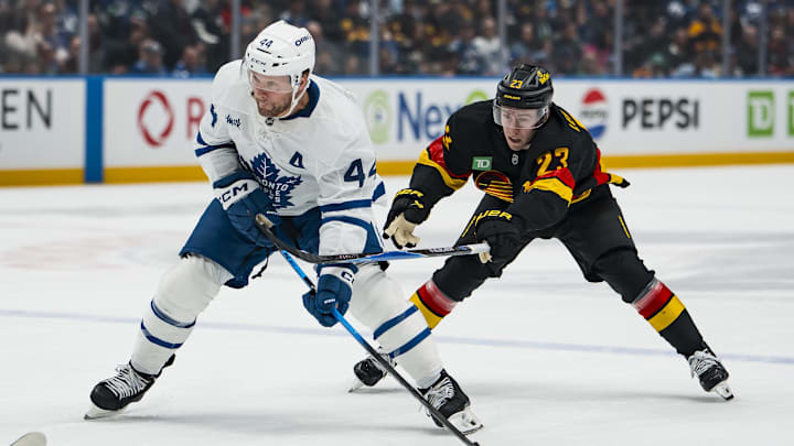 Jan 31, 2026; Vancouver, British Columbia, CAN; Vancouver Canucks forward Jonathan Lekkerimaki (23) stick checks Toronto Maple Leafs defenseman Morgan Rielly (44) in the first period at Rogers Arena. Mandatory Credit: Bob Frid-Imagn Images