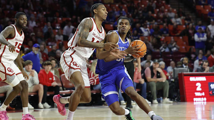 Feb 26, 2025; Norman, Oklahoma, USA; Kentucky Wildcats guard Otega Oweh (00) drives to the basket around Oklahoma Sooners forward Jalon Moore (14) during the first half at Lloyd Noble Center.