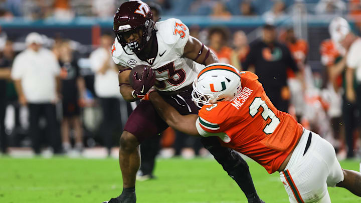 Sep 27, 2024; Miami Gardens, Florida, USA; Virginia Tech Hokies running back Bhayshul Tuten (33) runs with the football as Miami Hurricanes defensive lineman Akheem Mesidor (3) attempts a tackle during the second quarter at Hard Rock Stadium. Mandatory Credit: Sam Navarro-Imagn Images