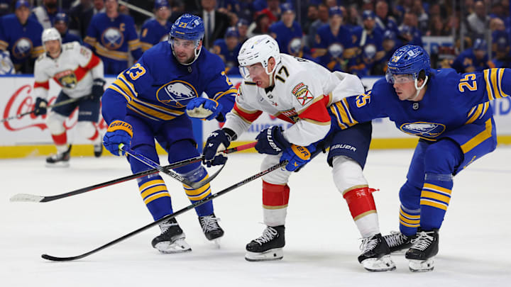 Oct 12, 2024; Buffalo, New York, USA;  Buffalo Sabres defenseman Mattias Samuelsson (23), Florida Panthers center Evan Rodrigues (17) and Buffalo Sabres defenseman Owen Power (25) race to a loose puck during the third period at KeyBank Center. Mandatory Credit: Timothy T. Ludwig-Imagn Images