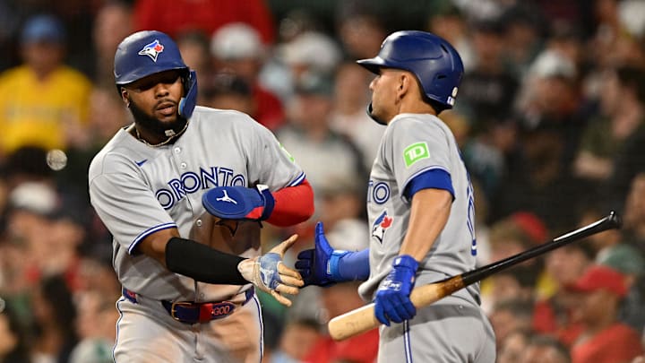 Jun 27, 2025; Boston, Massachusetts, USA; Toronto Blue Jays first baseman Vladimir Guerrero Jr. (27) high-fives second baseman Andres Gimenez (0) after scoring a run against the Boston Red Sox during the eighth inning at Fenway Park. Mandatory Credit: Brian Fluharty-Imagn Images