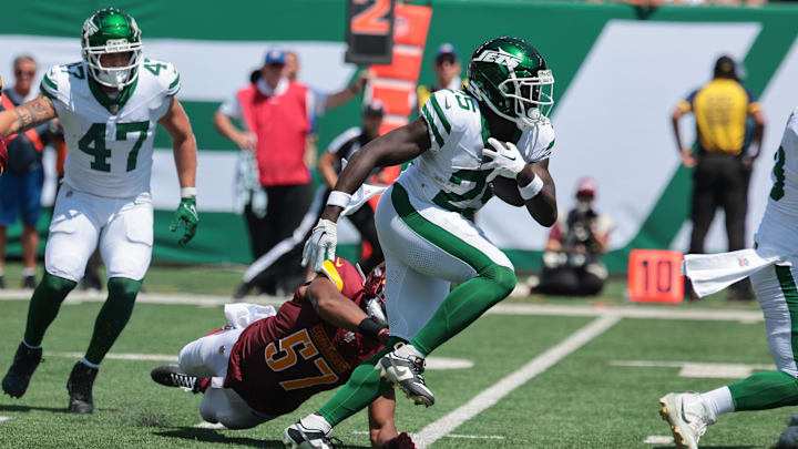 Aug 10, 2024; East Rutherford, New Jersey, USA; New York Jets running back Israel Abanikanda (25) carries the ball as Washington Commanders linebacker Anthony Pittman (57) tackles during the second half at MetLife Stadium. Mandatory Credit: Vincent Carchietta-Imagn Images