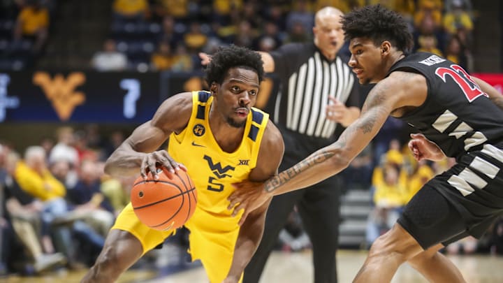 Feb 19, 2025; Morgantown, West Virginia, USA; West Virginia Mountaineers guard Toby Okani (5) dribbles against Cincinnati Bearcats forward Dillon Mitchell (23) during the first half at WVU Coliseum. Mandatory Credit: Ben Queen-Imagn Images