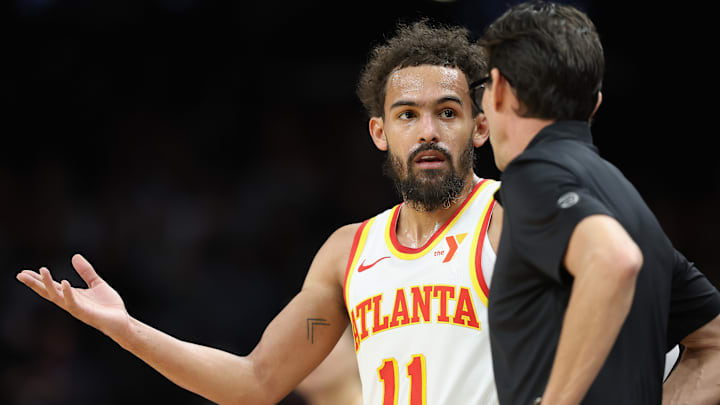 Trae Young #11 of the Atlanta Hawks speaks with head coach Quin Snyder.
