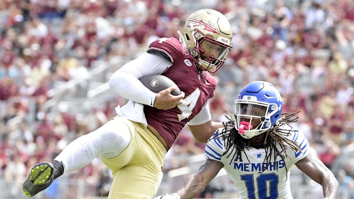 Sep 14, 2024; Tallahassee, Florida, USA; Florida State Seminoles quarterback DJ Uiagalelei (4) leaps against Memphis Tigers defensive back AJ Watts (10) and defensive back Greg Rubin (24) during the second half at Doak S. Campbell Stadium. Mandatory Credit: Melina Myers-Imagn Images
