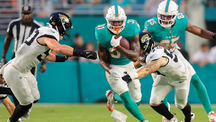 Miami Dolphins running back Ollie Gordon II (31) runs with the football past Jacksonville Jaguars linebacker Dennis Gardeck (57) and linebacker Branson Combs (50) during the second quarter at Hard Rock Stadium. Miami Dolphins running back Ollie Gordon II (31) runs with the football past Jacksonville Jaguars linebacker Dennis Gardeck (57) and linebacker Branson Combs (50) during the second quarter at Hard Rock Stadium.
