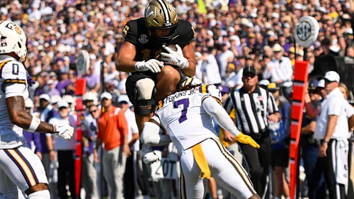 Oct 18, 2025; Nashville, Tennessee, USA;  Vanderbilt Commodores tight end Cole Spence (16) hurdles over Louisiana State Tigers linebacker Harold Perkins Jr. (7) during the first half at FirstBank Stadium. Mandatory Credit: Steve Roberts-Imagn Images