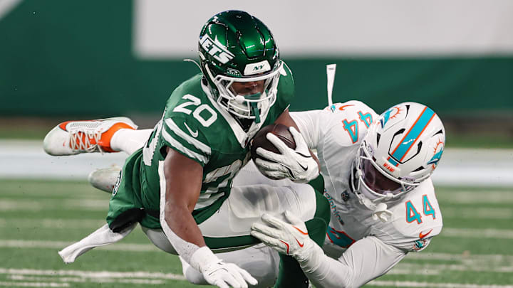 Jan 5, 2025; East Rutherford, New Jersey, USA; New York Jets running back Breece Hall (20) is tackled by Miami Dolphins linebacker Chop Robinson (44) during the first half at MetLife Stadium. Mandatory Credit: Vincent Carchietta-Imagn Images
