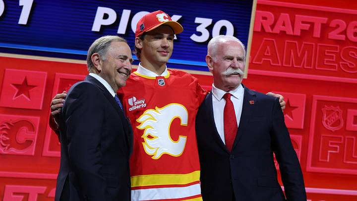 Jun 26, 2026; Buffalo, New York, USA; Jack Hextall reacts beside NHL commissioner Gary Bettman and former NHL player Lanny McDonald after being selected with the thirtieth pick in the first round of the 2026 NHL Draft by the Calgary Flames at KeyBank Center. Mandatory Credit: Timothy T. Ludwig-Imagn Images