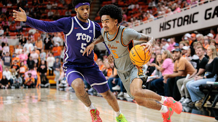 Feb 14, 2026; Stillwater, Oklahoma, USA; Oklahoma State Cowboys guard Vyctorius Miller (5) drives to the basket around TCU Horned Frogs forward Micah Robinson (5) during the first half at Gallagher-Iba Arena. Mandatory Credit: William Purnell-Imagn Images