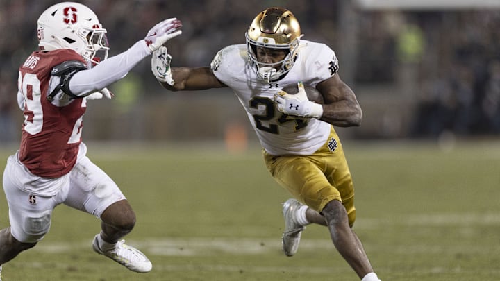 Nov 29, 2025; Stanford, California, USA;  Notre Dame Fighting Irish running back Jadarian Price (24) runs with the football against Stanford Cardinal safety Darrius Davis (29) during the first quarter at Stanford Stadium. Mandatory Credit: Stan Szeto-Imagn Images