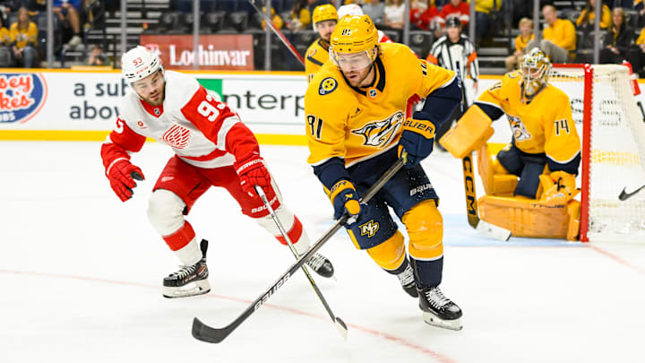Oct 19, 2024; Nashville, Tennessee, USA; Nashville Predators center Jonathan Marchessault (81) skates as Detroit Red Wings right wing Alex DeBrincat (93) pokes at the puck during the second period at Bridgestone Arena. Mandatory Credit: Steve Roberts-Imagn Images