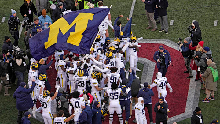 Michigan football players plant their team’s flag at midfield following Saturday’s NCAA Division I football game against the Ohio State Buckeyes at Ohio Stadium. The Michigan Wolverines won the game 13-10.