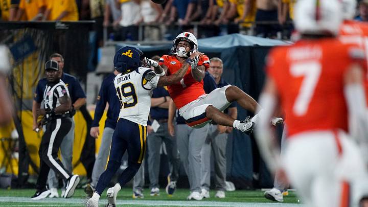 Sep 19, 2026; Charlotte, North Carolina, USA;  Virginia Cavaliers receiver Rico Flores (1) is upended by West Virginia Mountaineers cornerback Nick Taylor (19) during the second half at Bank of America Stadium.  Mandatory Credit: Jim Dedmon-Imagn Images