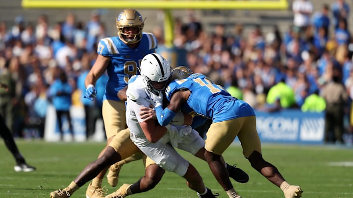 Oct 4, 2025; Pasadena, California, USA;  Penn State Nittany Lions quarterback Drew Allar (15) takes hits from UCLA Bruins linebacker Jalen Woods (9) and defensive back Rodrick Pleasant (18) during the fourth quarter at Rose Bowl. Mandatory Credit: Kiyoshi Mio-Imagn Images