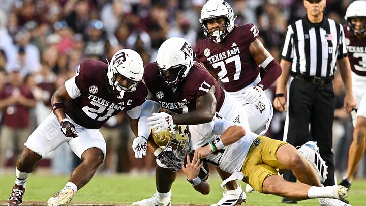 Aug 31, 2024; College Station, Texas, USA;  Texas A&M Aggies linebacker Taurean York (21) and defensive lineman Albert Regis (17) tackle Notre Dame Fighting Irish quarterback Riley Leonard (13) during the second quarter at Kyle Field. Mandatory Credit: Maria Lysaker-Imagn Images