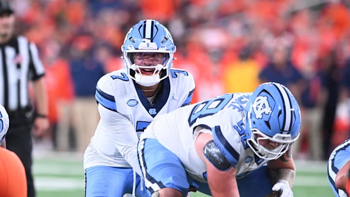 Oct 31, 2025; Syracuse, New York, USA; North Carolina Tar Heels quarterback Gio Lopez (7) with center Austin Blaske (58) at the line of scrimmage in the third quarter against the Syracuse Orange at the JMA Wireless Dome. Mandatory Credit: Mark Konezny-Imagn Images Oct 31, 2025; Syracuse, New York, USA; North Carolina Tar Heels quarterback Gio Lopez (7) with center Austin Blaske (58) at the line of scrimmage in the third quarter against the Syracuse Orange at the JMA Wireless Dome. Mandatory Credit: Mark Konezny-Imagn Images