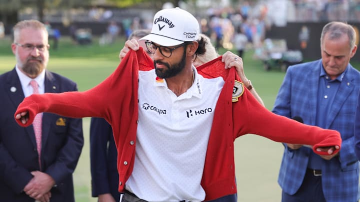 Mar 8, 2026; Orlando, Florida, USA;  Akshay Bhatia celebrates by putting on the iconic red alpaca sweater following his win on the 18th green after a playoff victory in the Arnold Palmer Invitational golf tournament. Mandatory Credit: Reinhold Matay-Imagn Images