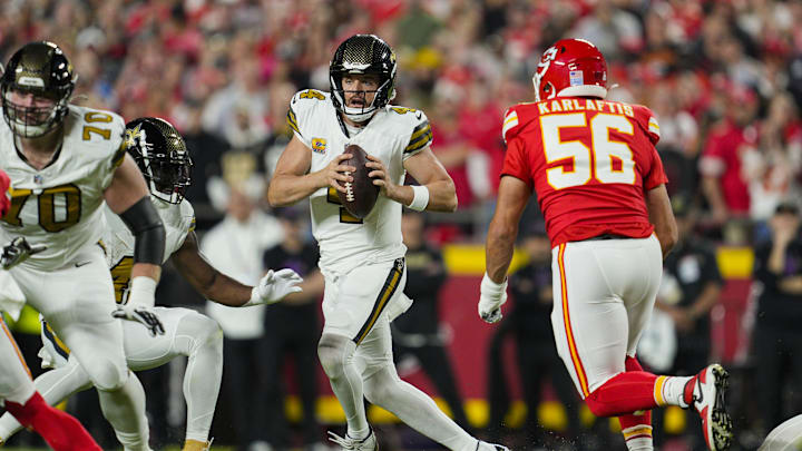 Oct 7, 2024; Kansas City, Missouri, USA; New Orleans Saints quarterback Derek Carr (4) scrambles form Kansas City Chiefs defensive end George Karlaftis (56) during the first half at GEHA Field at Arrowhead Stadium. Mandatory Credit: Jay Biggerstaff-Imagn Images