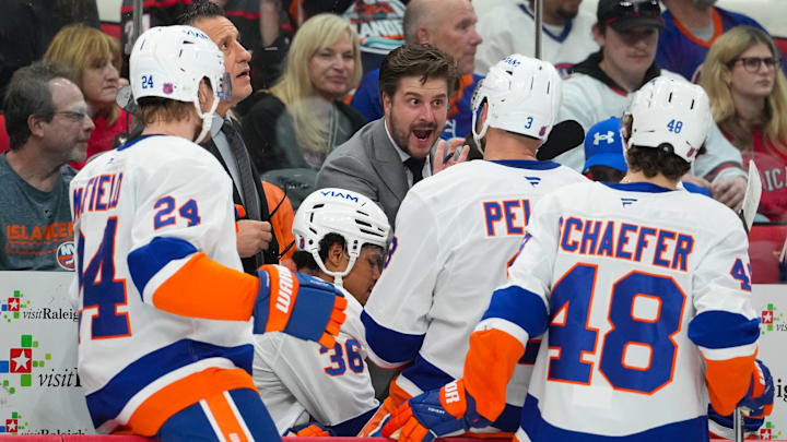 Apr 4, 2026; Raleigh, North Carolina, USA;  New York Islanders assistant coach Benoit Desrosiers talks to defenseman Scott Mayfield (24) defenseman Ryan Pulock (6) defenseman Isaiah George (36) and defenseman Matthew Schaefer (48) against the Carolina Hurricanes during the first period at Lenovo Center. Mandatory Credit: James Guillory-Imagn Images