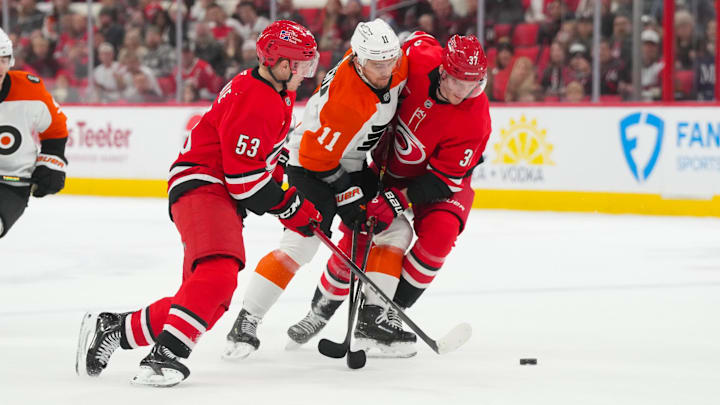 Dec 14, 2025; Raleigh, North Carolina, USA; Carolina Hurricanes right wing Jackson Blake (53) and right wing Andrei Svechnikov (37) battle Philadelphia Flyers right wing Travis Konecny (11) for the puck in the overtime at Lenovo Center. Mandatory Credit: James Guillory-Imagn Images
