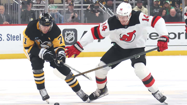 Mar 15, 2025; Pittsburgh, Pennsylvania, USA;  Pittsburgh Penguins center Evgeni Malkin (71) and New Jersey Devils right wing Nathan Bastian (14) battle for the puck during the second period at PPG Paints Arena. Mandatory Credit: Charles LeClaire-Imagn Images