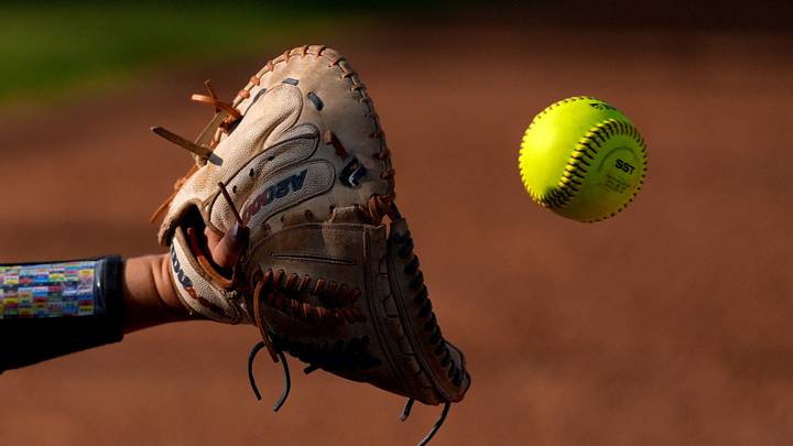 The ball goes into a catcher's glove during warmups between innings during a high school softball game. The ball goes into a catcher's glove during warmups between innings during a high school softball game.