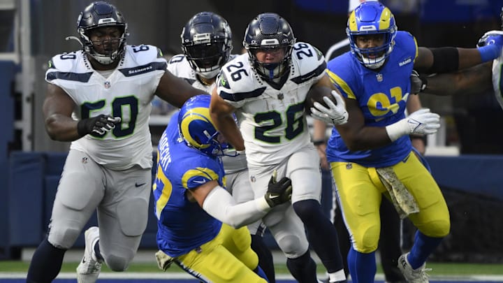 Nov 19, 2023; Inglewood, California, USA; Seattle Seahawks running back Zach Charbonnet (26) runs against Los Angeles Rams linebacker Michael Hoecht (97) in the first quarter at SoFi Stadium. Mandatory Credit: Robert Hanashiro-Imagn Images