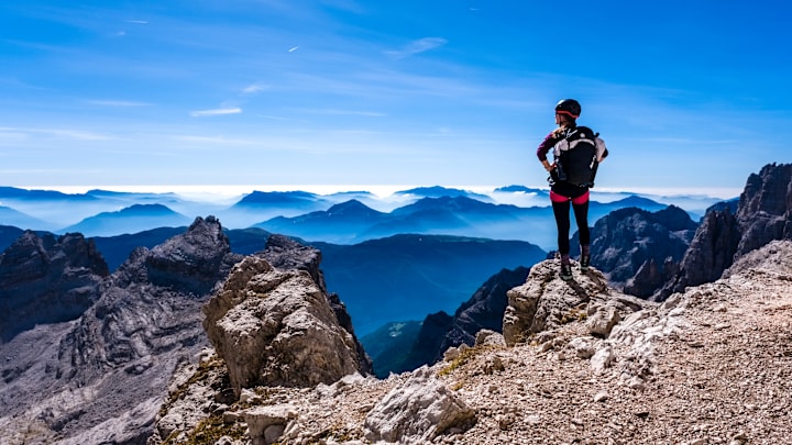 A climber is looking at silhouettes of valleys and mountains...