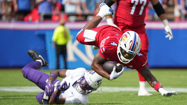 Sep 28, 2024; Kansas City, Missouri, USA; Kansas Jayhawks running back Devin Neal (4) goes airborne as TCU Horned Frogs safety Jamel Johnson (2) makes the take during the first half at GEHA Field at Arrowhead Stadium. Mandatory Credit: Denny Medley-Imagn Images