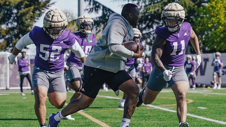 Armond Hawkins, defensive analyst, runs the Husky linebackers through a drill. 