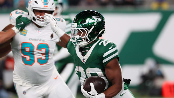 Jan 5, 2025; East Rutherford, New Jersey, USA; New York Jets running back Breece Hall (20) runs with the ball while being pursued by Miami Dolphins defensive tackle Calais Campbell (93) during the second quarter at MetLife Stadium. Mandatory Credit: Ed Mulholland-Imagn Images