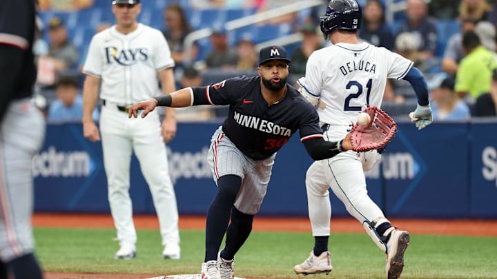 Sep 5, 2024; St. Petersburg, Florida, USA; Tampa Bay Rays outfielder Jonny DeLuca (21) runs out an errant throw to Minnesota Twins first baseman Carlos Santana (30) in the third inning at Tropicana Field. Mandatory Credit: Nathan Ray Seebeck-Imagn Images Sep 5, 2024; St. Petersburg, Florida, USA; Tampa Bay Rays outfielder Jonny DeLuca (21) runs out an errant throw to Minnesota Twins first baseman Carlos Santana (30) in the third inning at Tropicana Field. Mandatory Credit: Nathan Ray Seebeck-Imagn Images