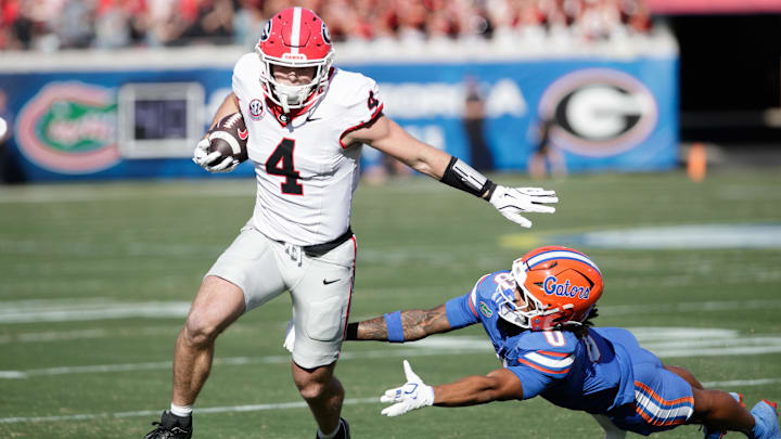Nov 1, 2025; Jacksonville, Florida, USA; Georgia Bulldogs tight end Oscar Delp (4) evades Florida Gators defensive back Sharif Denson (0) in the first quarter at EverBank Stadium. Mandatory Credit: Travis Register-Imagn Images