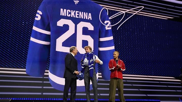 Jun 26, 2026; Buffalo, New York, USA; Gavin McKenna puts on a sweater beside NHL commissioner Gary Bettman and singer Justin Bieber after being selected with the first pick in the first round of the 2026 NHL Draft by the Toronto Maple Leafs at KeyBank Center. Mandatory Credit: Timothy T. Ludwig-Imagn Images