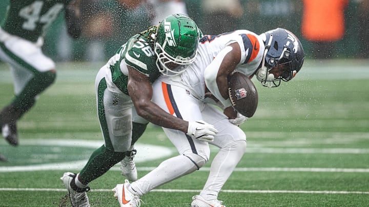 Sep 29, 2024; East Rutherford, New Jersey, USA; Denver Broncos running back Tyler Badie (28) fumbles after being hit by New York Jets linebacker Quincy Williams (56) during the first half at MetLife Stadium. Mandatory Credit: Vincent Carchietta-Imagn Images