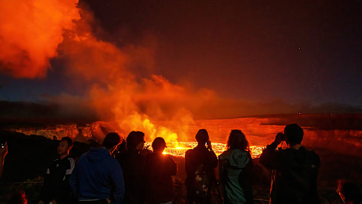 Hikers watch Kīlauea erupt from the safety of the trail.