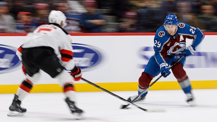 Feb 26, 2025; Denver, Colorado, USA; Colorado Avalanche center Nathan MacKinnon (29) controls the puck as New Jersey Devils defenseman Brenden Dillon (5) defends in the second period at Ball Arena. Mandatory Credit: Isaiah J. Downing-Imagn Images