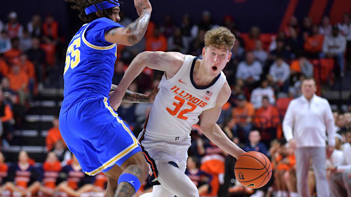 Feb 11, 2025; Champaign, Illinois, USA;  Illinois Fighting Illini guard Kasparas Jakucionis (32) drives the ball against UCLA Bruins guard Skyy Clark (55) during the first half at State Farm Center. Mandatory Credit: Ron Johnson-Imagn Images