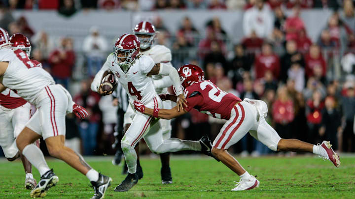 Nov 23, 2024; Norman, Oklahoma, USA; Alabama Crimson Tide quarterback Jalen Milroe (4) breaks a tackle by Oklahoma Sooners defensive back Peyton Bowen (22) during the third quarter at Gaylord Family-Oklahoma Memorial Stadium. Mandatory Credit: William Purnell-Imagn Images
