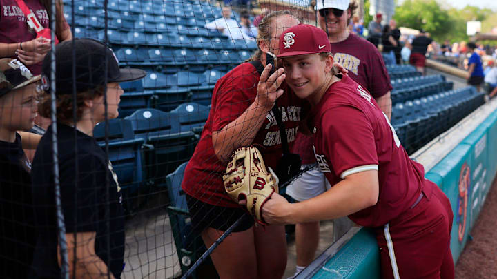 Florida State infielder Cal Fisher (4) is hugged through mesh netting before an NCAA baseball matchup at 121 Financial Ballpark in Jacksonville, Fla. Florida State defeated Florida 14-3.