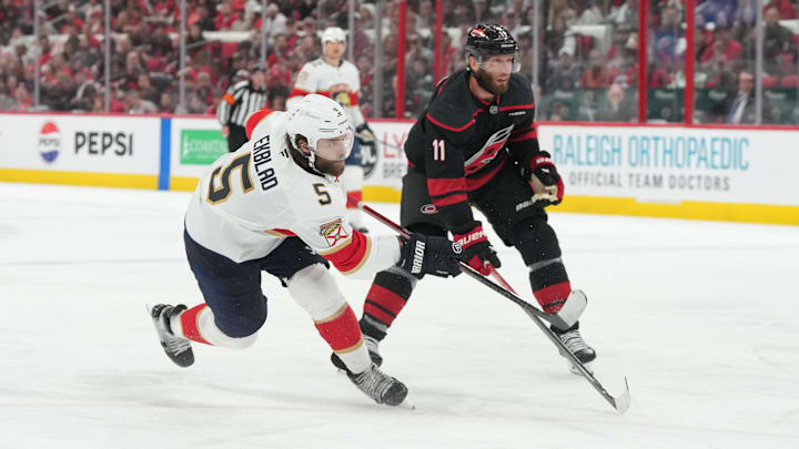 May 20, 2025; Raleigh, North Carolina, USA;  Florida Panthers defenseman Aaron Ekblad (5) shoots as Carolina Hurricanes forward Jordan Staal (11) defends during the second period in game one of the Eastern Conference Final of the 2025 Stanley Cup Playoffs at Lenovo Center. Mandatory Credit: James Guillory-Imagn Images