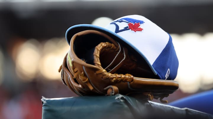 Mar 18, 2025; Sarasota, Florida, USA;  A detail view of a Toronto Blue Jays hat and glove against the Baltimore Orioles at Ed Smith Stadium.