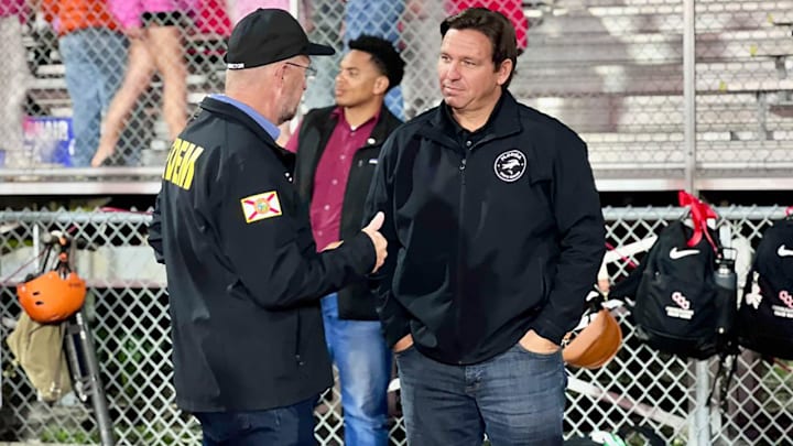 Florida governor Ron DeSantis chats with a first responder on the sideline of Friday's high school football game between Venice and Clearwater Central Catholic at Venice.